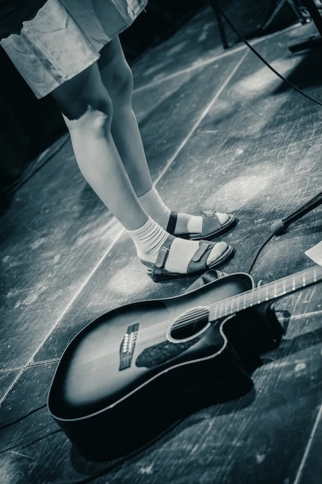 Performer with acoustic guitar on stage at Mengelmoes